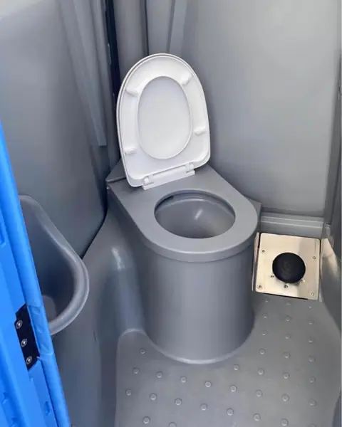 Inside a deluxe porta potty with a seat and corner sink