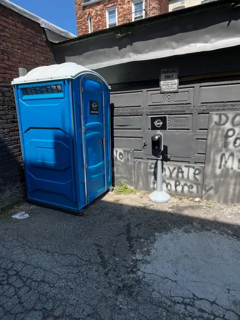 Blue porta potty beside a garage during a home renovation