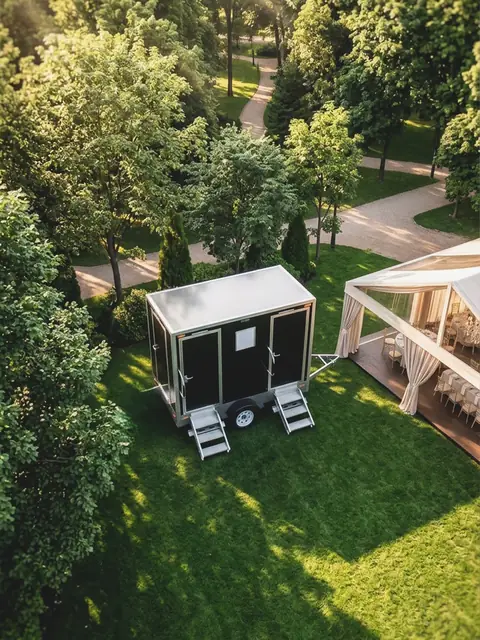 Restroom trailer on a lawn beside a wedding tent