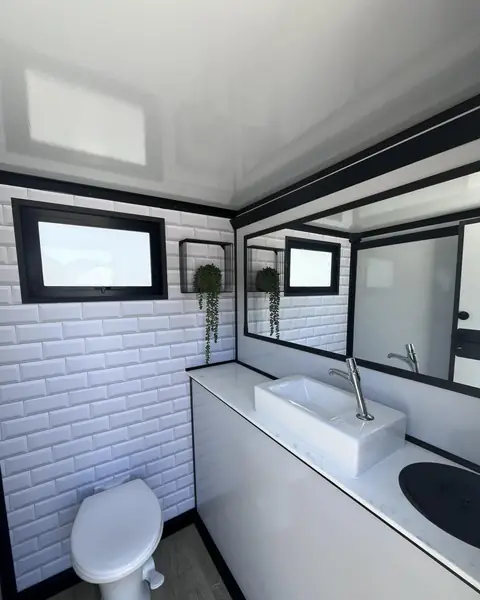 Restroom trailer interior with vanity sink, mirror and window