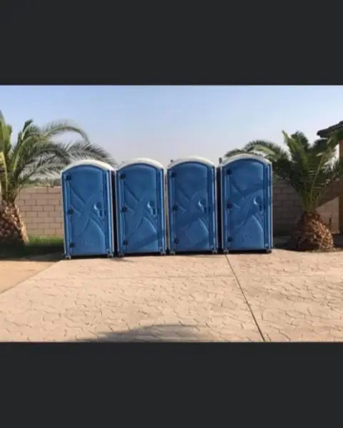 Row of four blue event porta potties on pavement